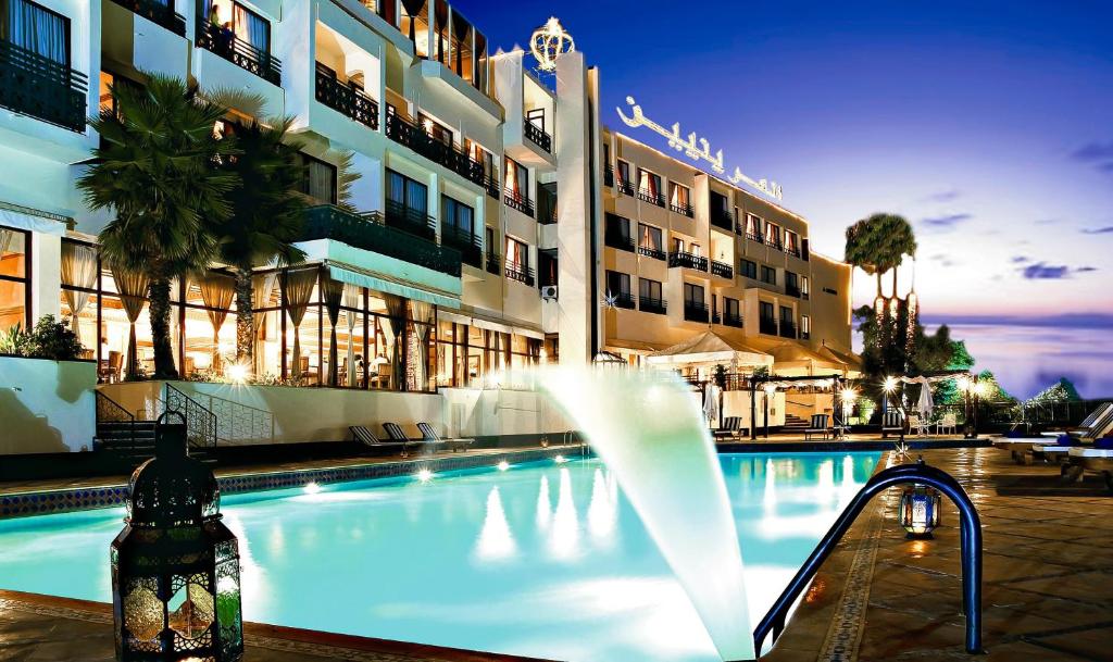 a swimming pool with a fountain in front of a building at Les Mérinides in Fès