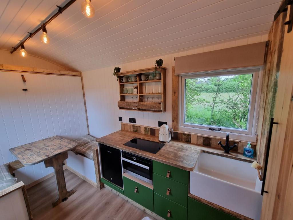 a kitchen with a sink and a window at Rusty - Shepherds hut sleeps up to 4 in Sidlesham