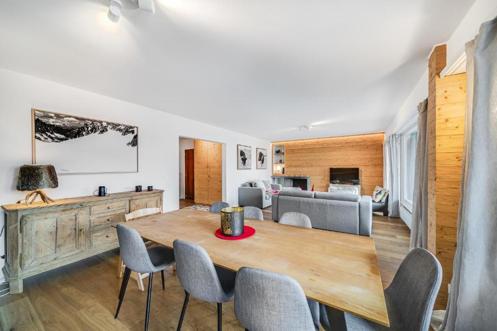 a dining room and living room with a wooden table and chairs at In the heart of Crans, fireplace and parking in Crans-Montana