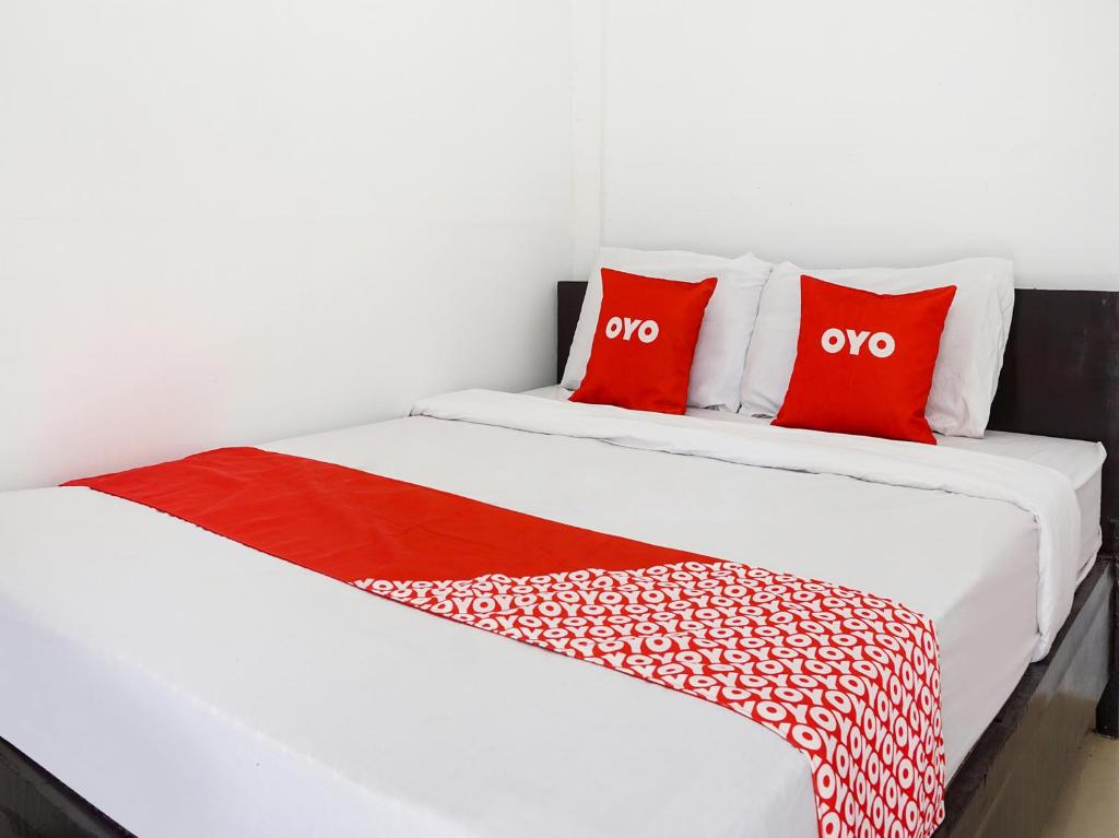 two beds with red and white pillows in a room at OYO 91544 Homestay Biru Blukid in Sidoarjo