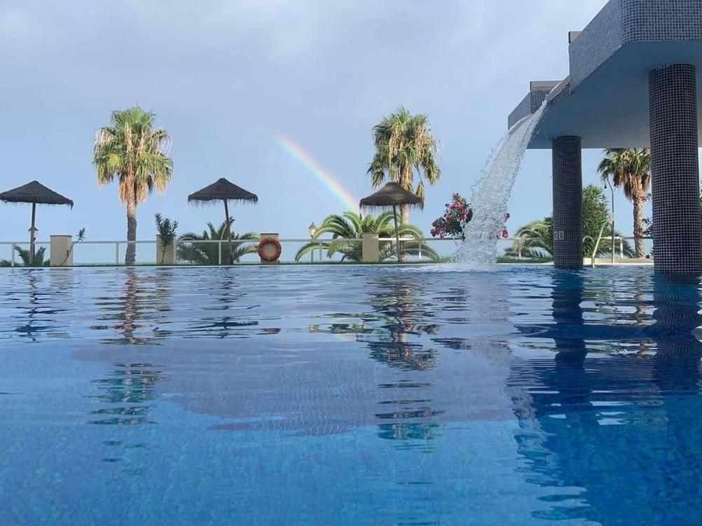 einem Pool mit einem Brunnen vor einem Gebäude in der Unterkunft Primera Linea De Playa in Roquetas de Mar