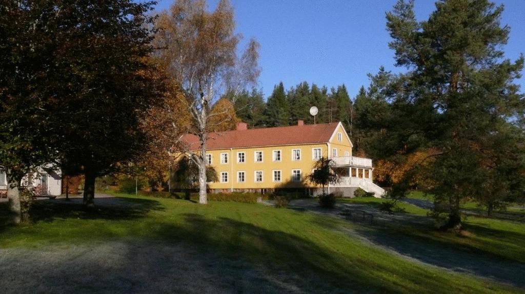 een groot geel huis met een rood dak bij Hotel PerOlofGården in Åsbro