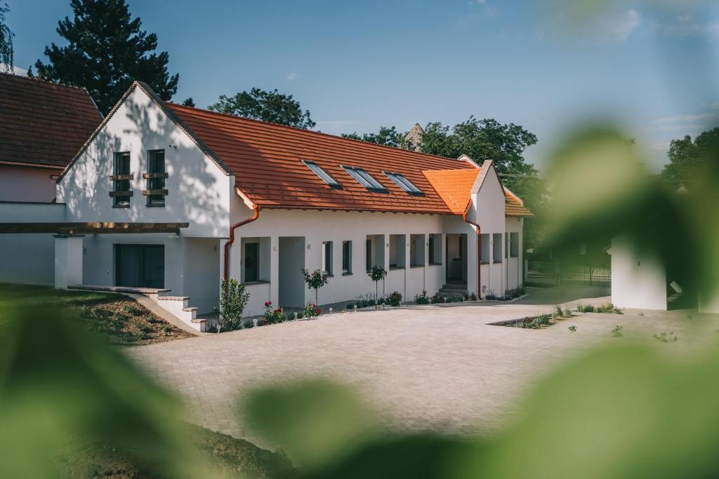 a white house with an orange roof at Kardamom Studio Apartman in Szigliget