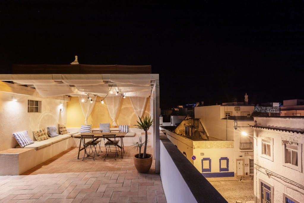 a balcony with a table and a couch on a roof at Casa ao Cubo in Olhão