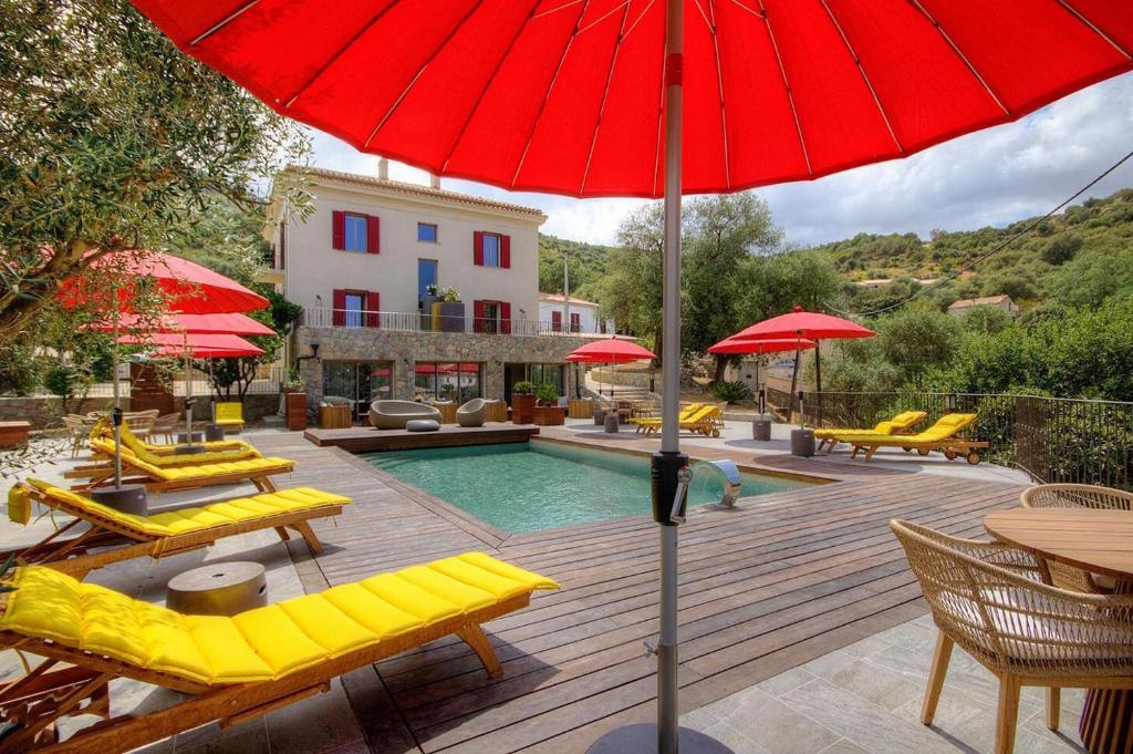 的住宿－Hôtel Casale Olmia，一个带黄色椅子和红色遮阳伞的游泳池