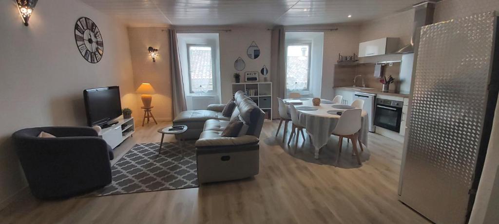 a living room with a couch and a table and a kitchen at l arbre à chats in Saint-Martin-de-Brômes