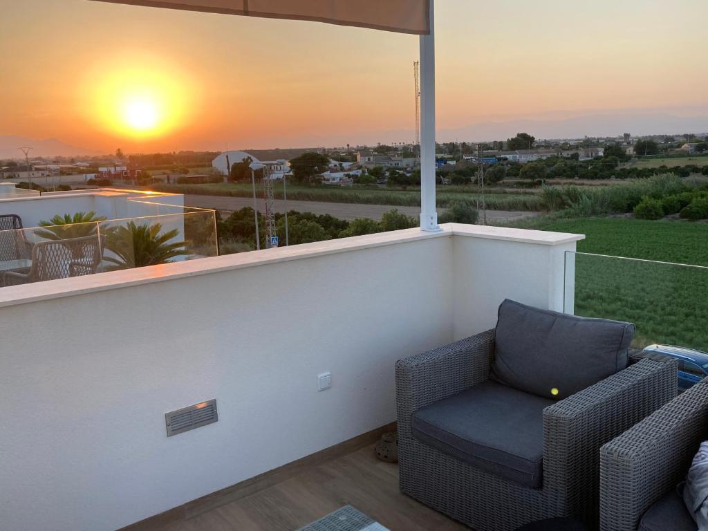 a balcony with a chair and a window with the sunset at Casa Flamencos in Rojales
