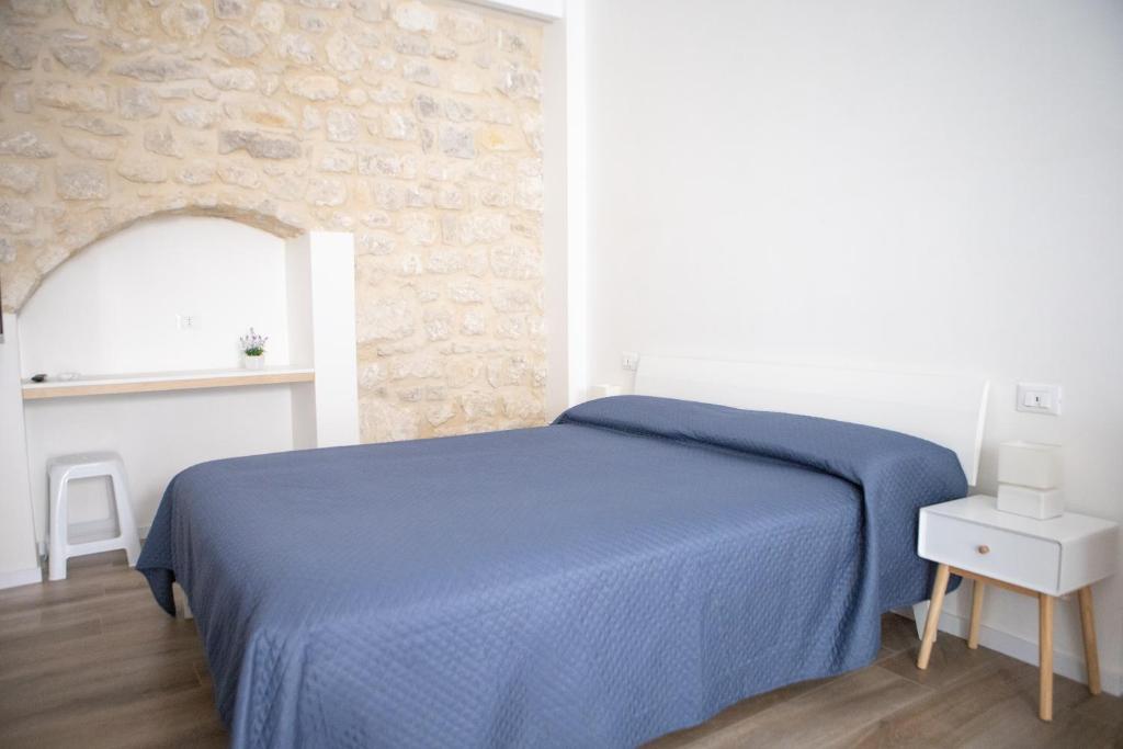 een slaapkamer met een blauw bed en een stenen muur bij CASA MAIOLICA in Modica