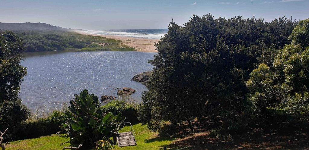 a bench sitting on a hill next to a body of water at Black Rock Haven in Scottburgh