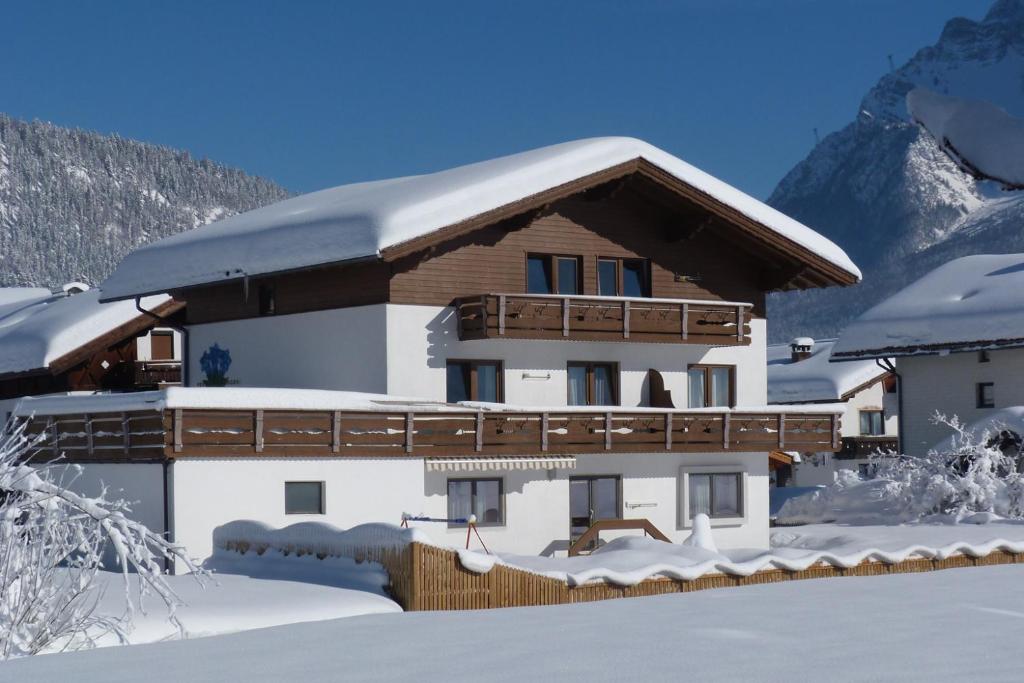 ein schneebedecktes Haus mit einem Berg im Hintergrund in der Unterkunft Haus Enzian in Lermoos