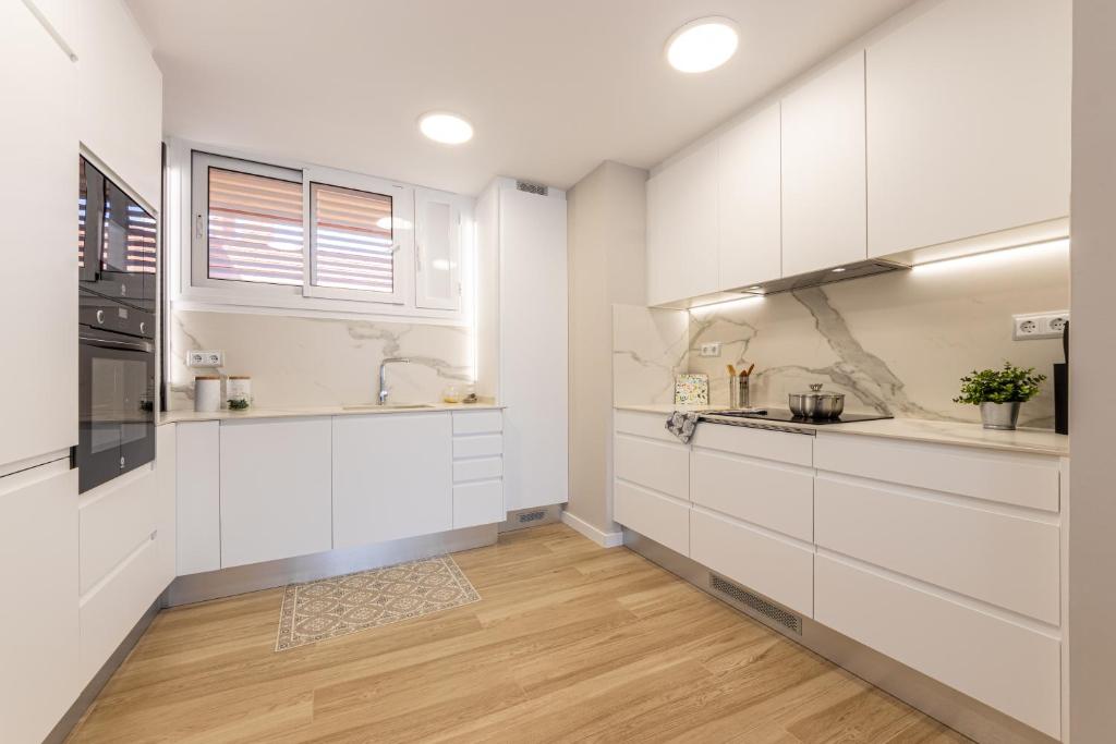 una cucina con armadietti bianchi e pavimenti in legno di HOMES & GO MAS D'EN GRAN a Cambrils