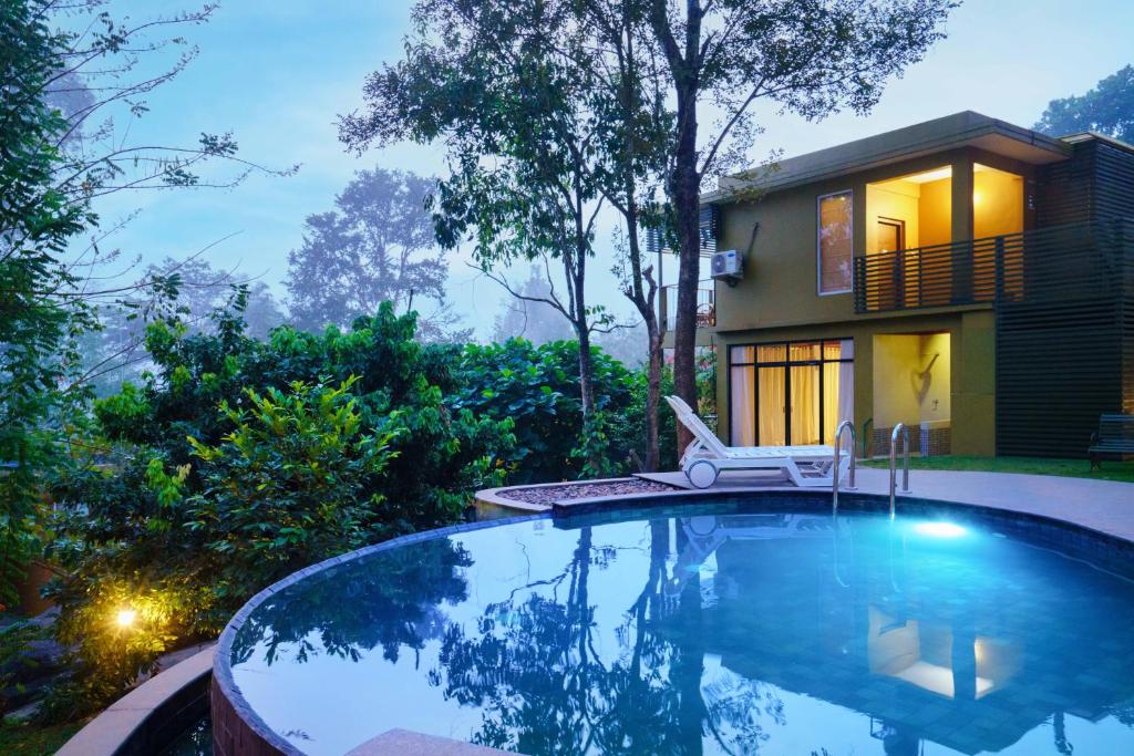a swimming pool in front of a house at Kuruva Island Resort And Spa - By KABINI BREEZE, Wayanad in Mananthavady