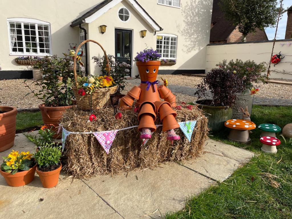 a large scarecrow sitting on a pile of hay in a garden at St Leonards Farmhouse in Blandford Forum