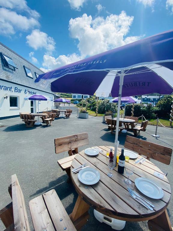 a wooden picnic table with an umbrella and plates on it at Croyde Bay Hotel or Self Catering in Croyde
