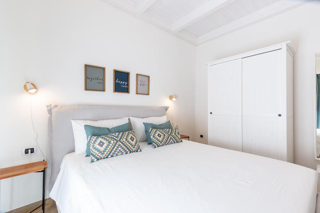 ein weißes Schlafzimmer mit einem weißen Bett und Kissen in der Unterkunft Casa Titina in Capoterra
