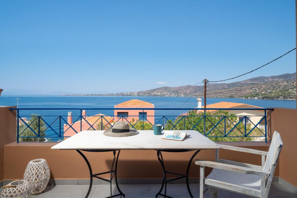 a table and chair on a balcony with a view of the ocean at Absolute Perdika Aegina in Perdika