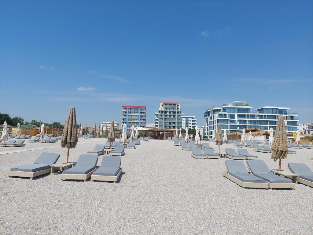 eine Reihe von Liegestühlen und Sonnenschirmen am Strand in der Unterkunft Blue Marina Clubbing Studio 5 in Mamaia