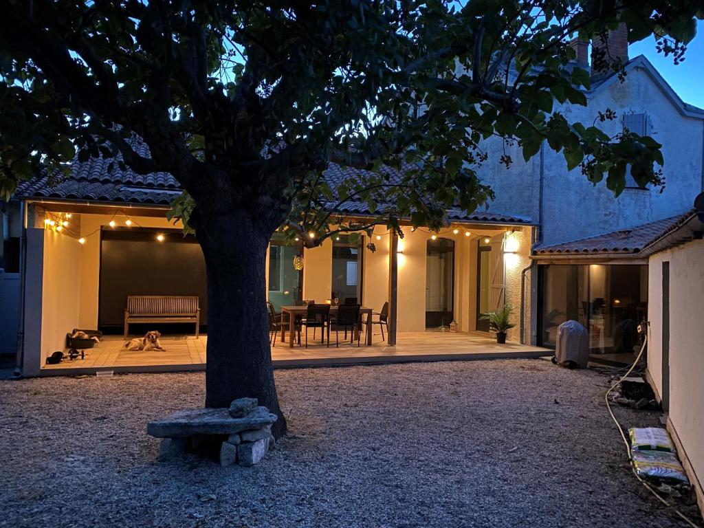 un árbol frente a una casa con un banco en Villa Paulownia - à 1,2km des plages - tout confort au coeur du bourg, en Jard-sur-Mer