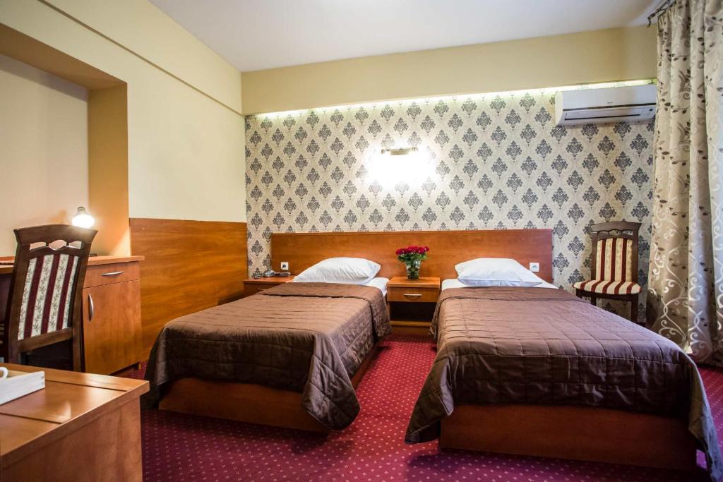 a hotel room with two beds and a table at Hotel Maksymilian in Krakow