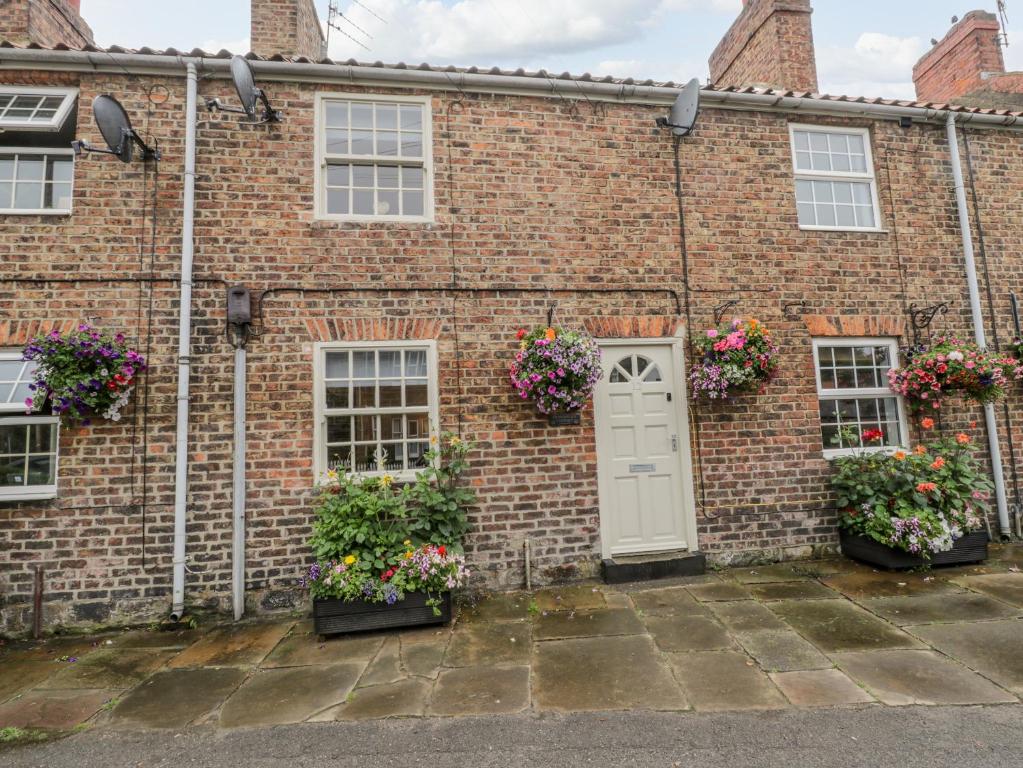 um edifício de tijolos com flores à frente em Henrietta's Cottage em Guisborough