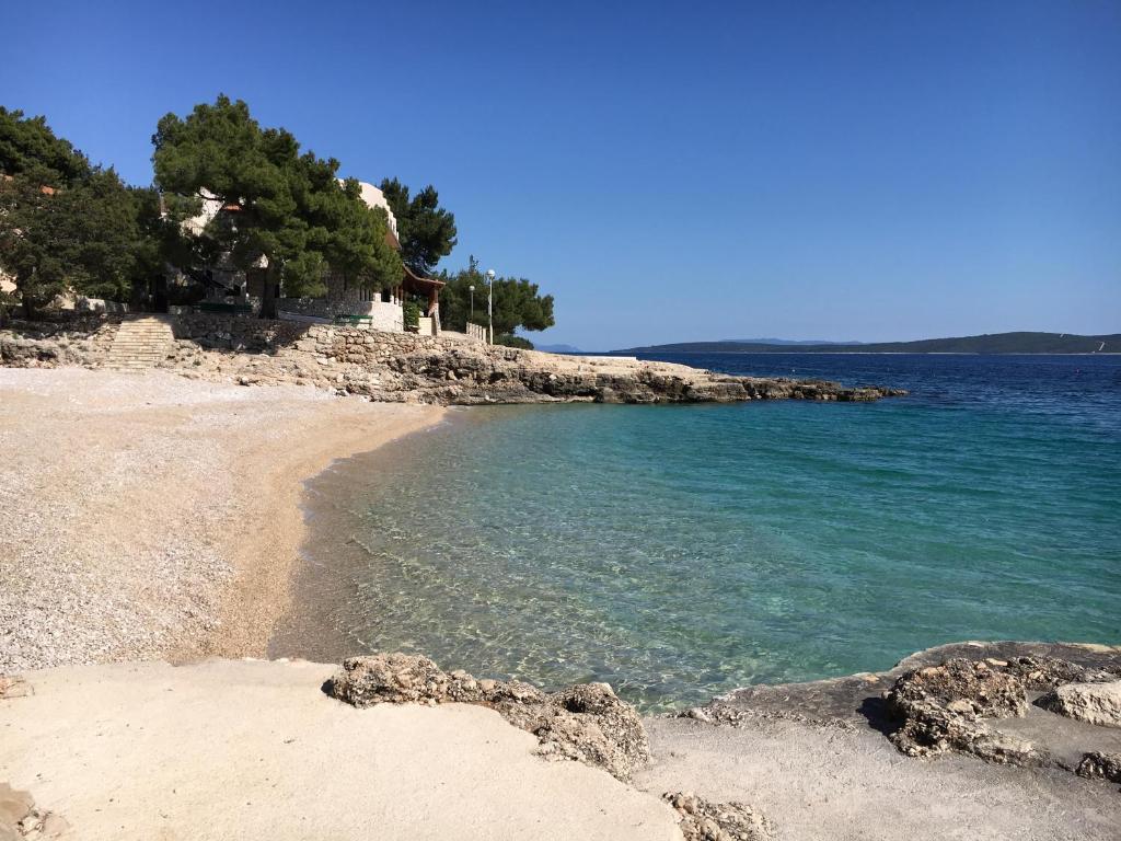 a beach with blue water and trees on the shore at Apartman ENA in Ivan Dolac