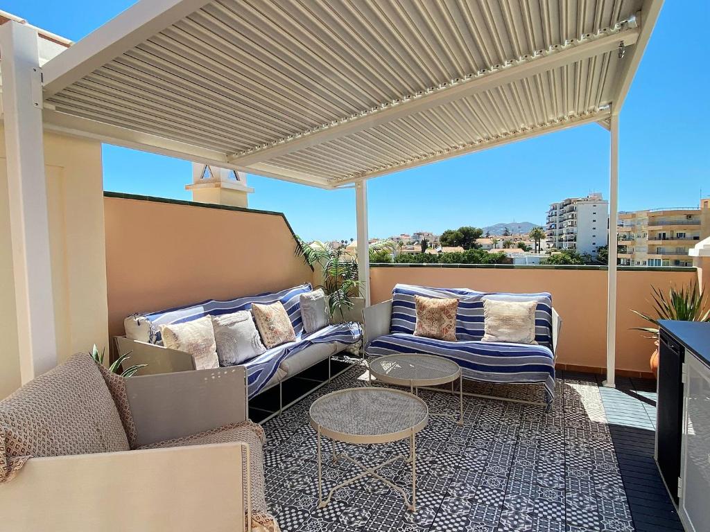eine Terrasse mit einem Sofa und Stühlen auf dem Balkon in der Unterkunft Villa La Dorada Burriana Casasol in Nerja