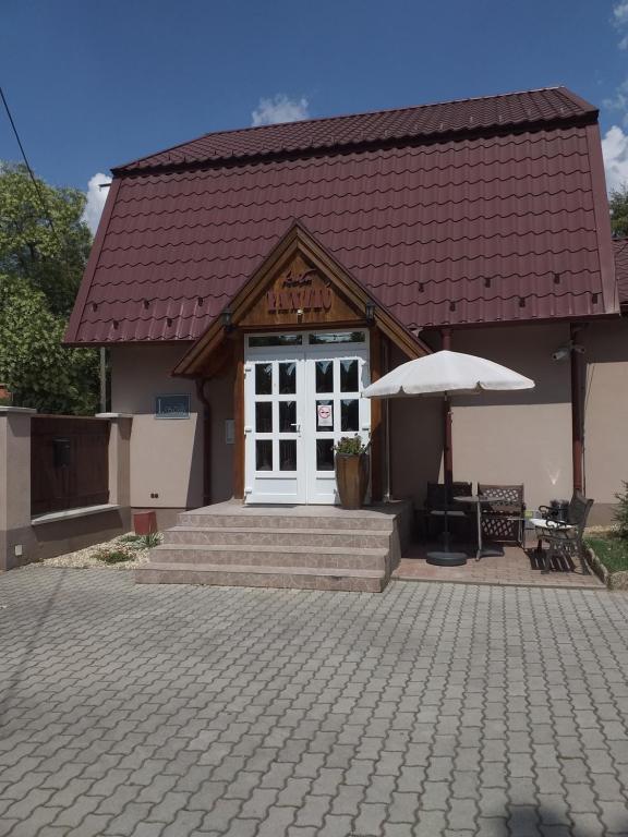 un edificio con una puerta blanca y una sombrilla en Kata Panzió en Oroszlány
