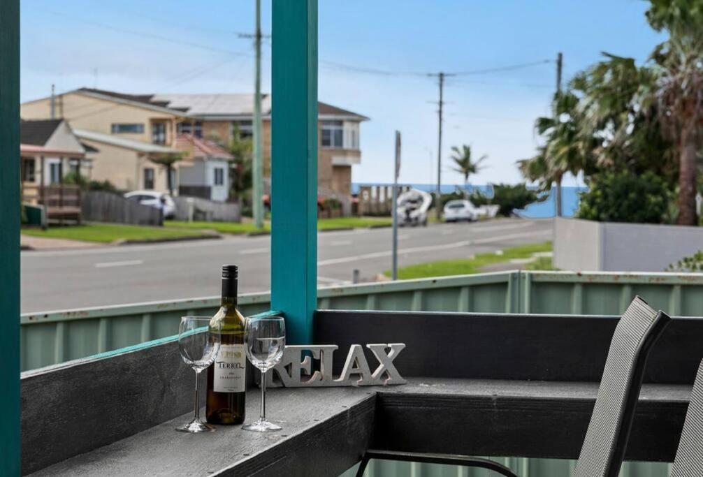 a bottle of wine and two glasses on a balcony at Coastal Vibes - Walk to beach, Marina, Cafes and Pubs in Shellharbour