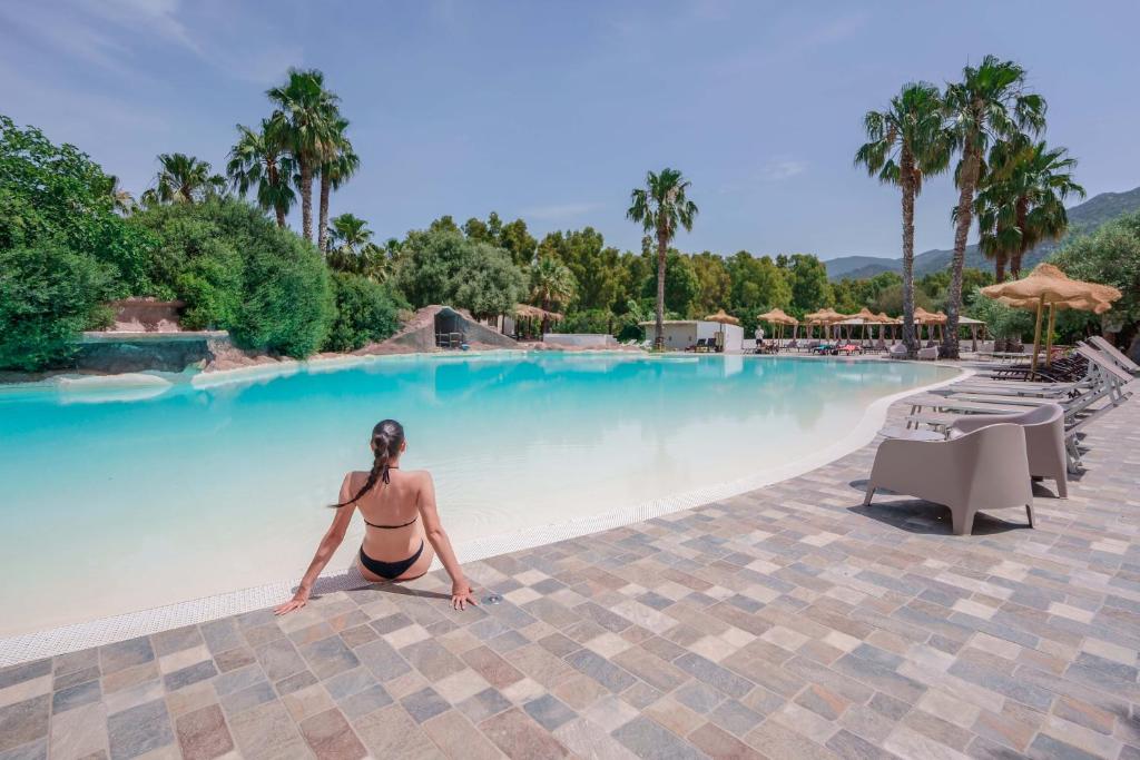 una mujer sentada en una piscina en un resort en Il Monastero, en Geremèas