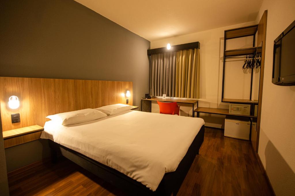 a bedroom with a large white bed in a room at ibis Betim in Betim