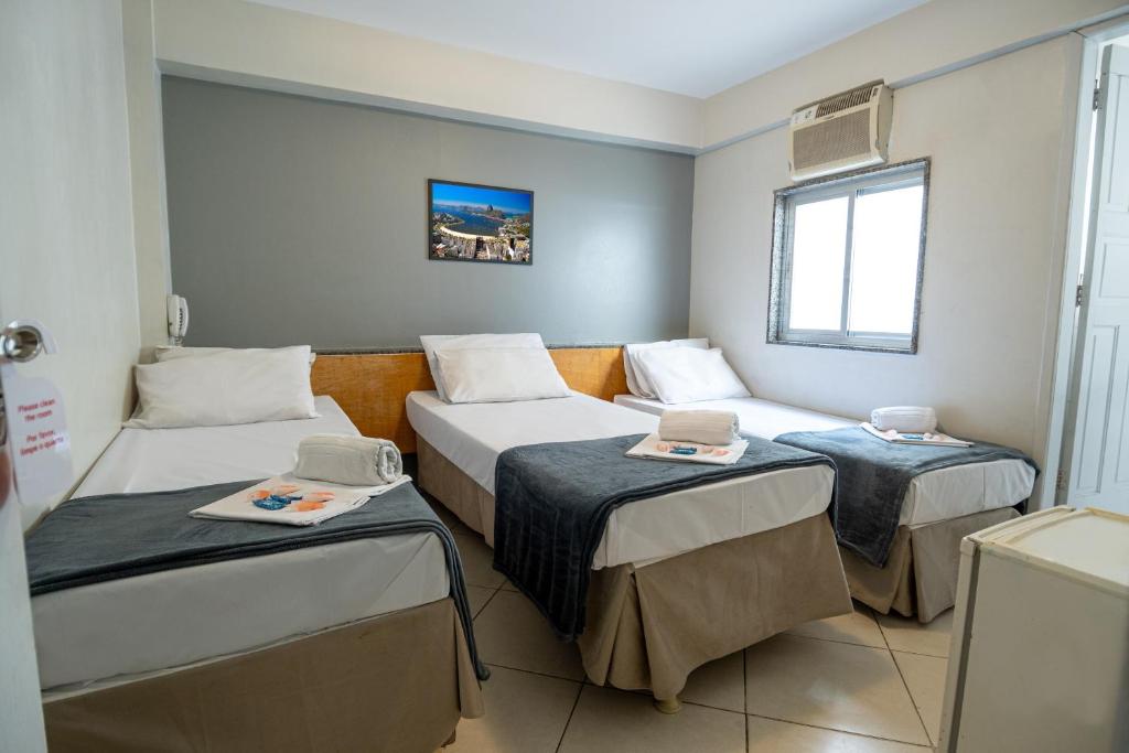 a room with three beds and a window at Hotel Vital, Rio de Janeiro in Rio de Janeiro