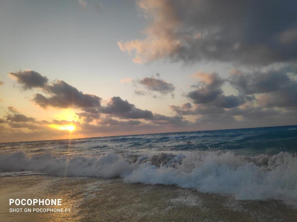 einen Sonnenuntergang am Strand mit dem Meer in der Unterkunft Grand hills North Coast - Families Only z44 in Dawwār ‘Abd Allāh