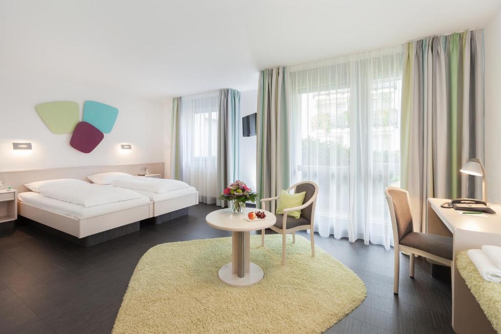Habitación de hotel con cama, mesa y sillas en Hotel Akazienhaus, en Herzogenaurach