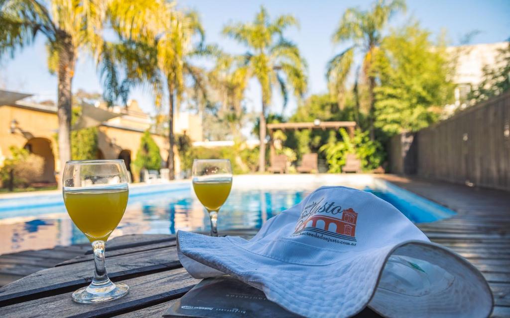 dos copas de vino y un sombrero en una mesa junto a una piscina en Hacienda Don Justo Hotel Boutique Spa en Colón