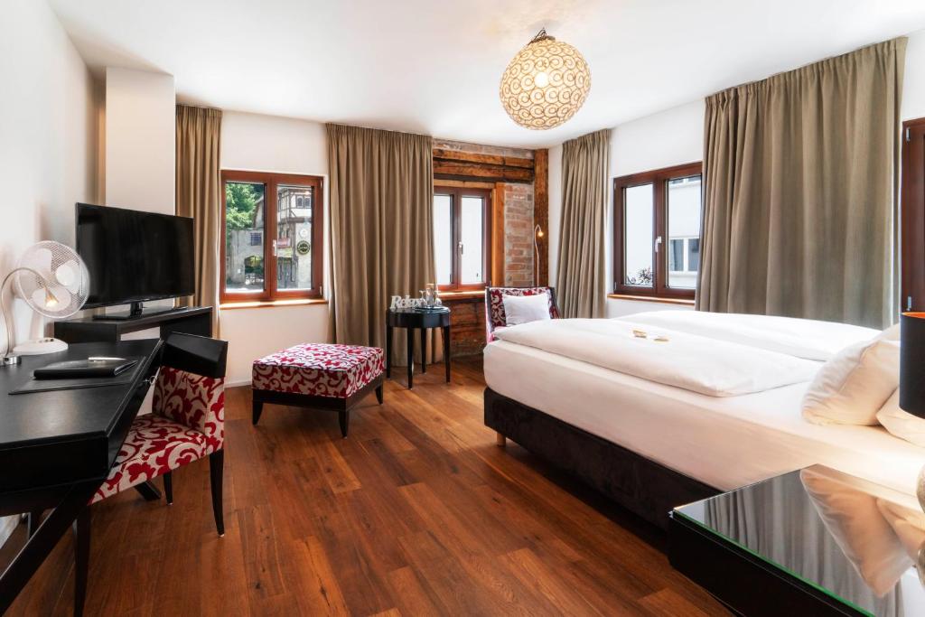 ラーベンスブルクにあるOchsen Hotel Am Mehlsackの大きなベッドとデスクが備わるホテルルームです。