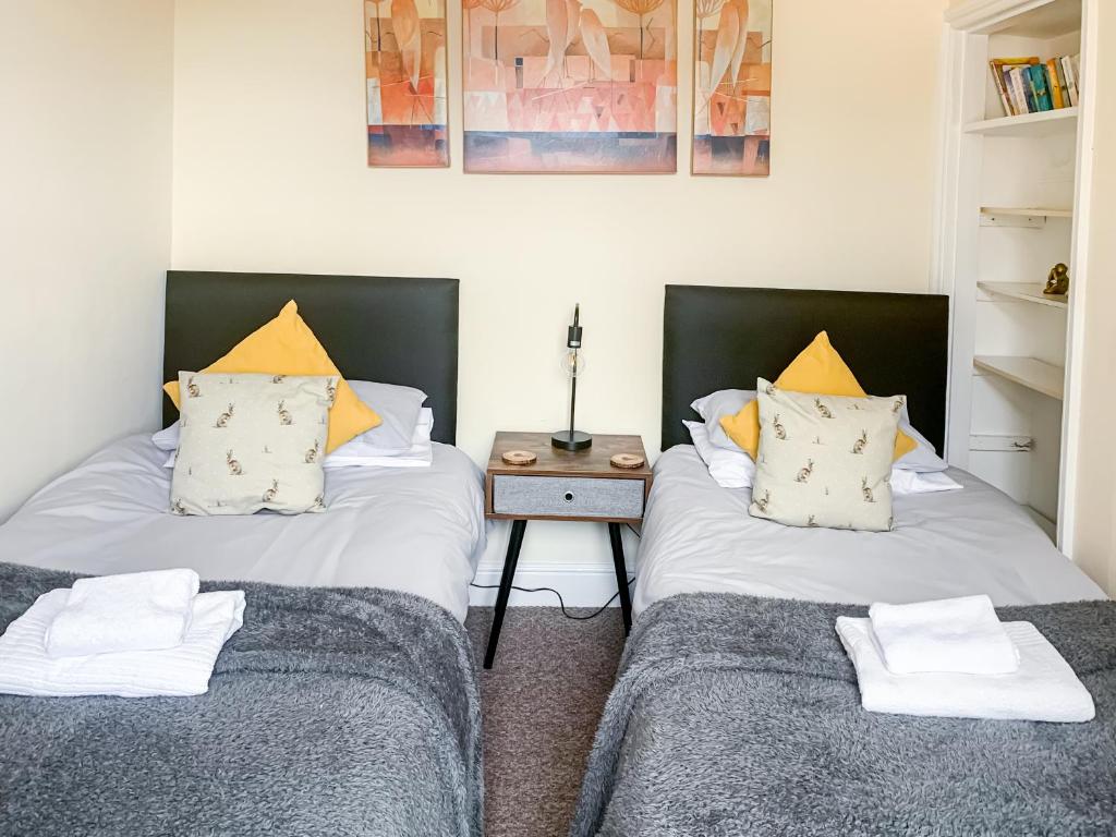 two beds in a room with a side table at Stay In The Heart Of York At Waverley Lodge - Free Parking - York Holiday Home in York