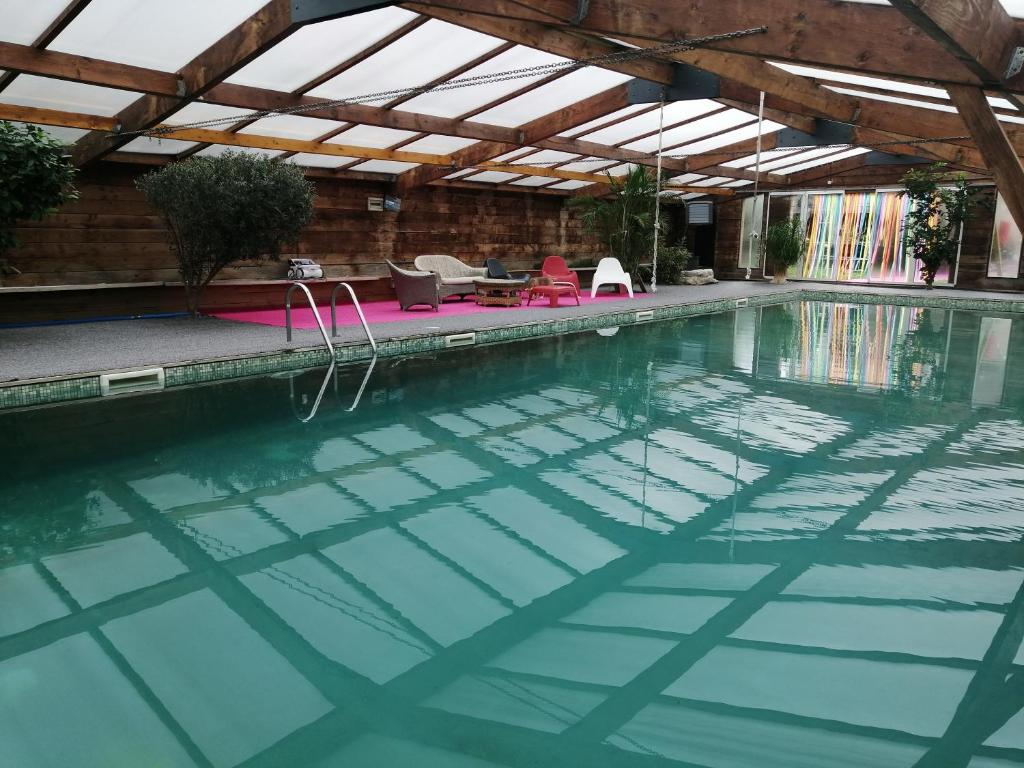 an indoor swimming pool with a roof and an outdoor swimming pool at Gîte-L'Ange Blanc 20 personnes in Lignières