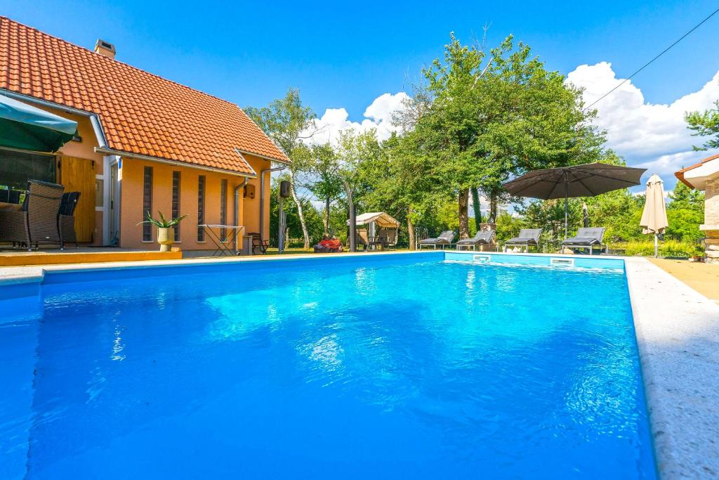 ein blauer Pool vor einem Haus in der Unterkunft Villa Suzana's Nature Hideout in Gospić