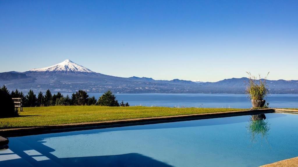 a large swimming pool with a mountain in the background at Hill & Sky Lodge in Pucón