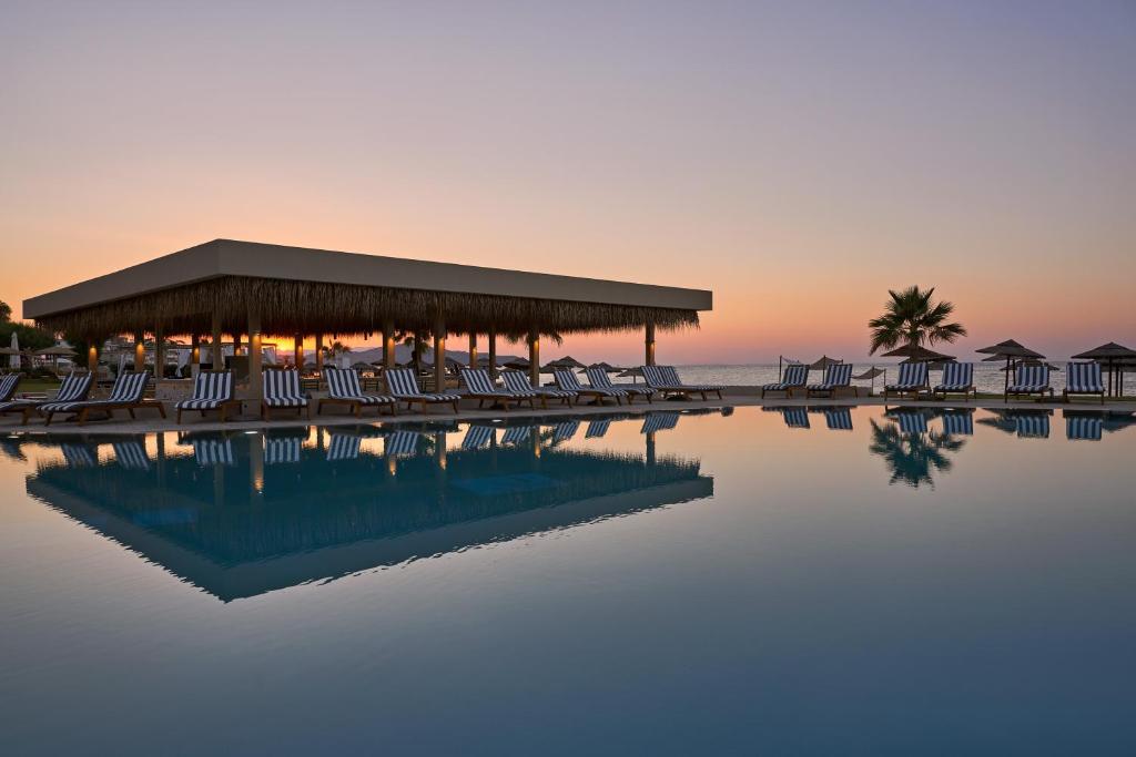 - une piscine avec des chaises et une jetée donnant sur l'océan dans l'établissement Atlantica Kalliston Resort - Adults Only, à Stalós