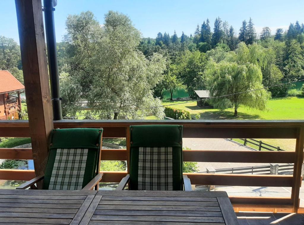 a table and chairs on a balcony with a view at Riverside Vacation House Mrežnica in Donji Zvečaj