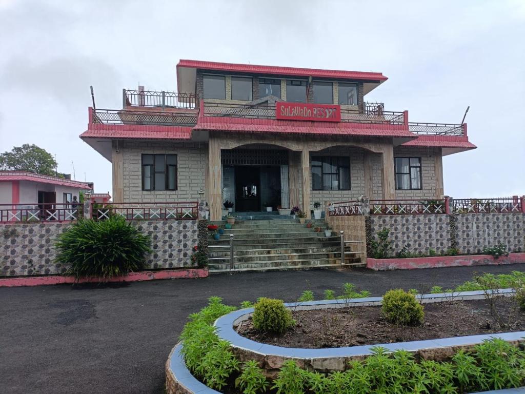 a house with a porch and stairs in front of it at Sulawado Resort in Cherrapunji