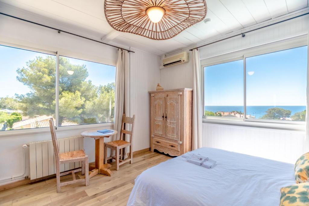 a bedroom with a bed and two large windows at Villa Paradis in Les Issambres