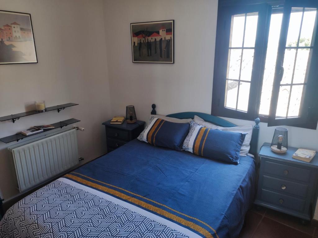 um quarto com uma cama azul e 2 janelas em Piso Blanco em Ronda