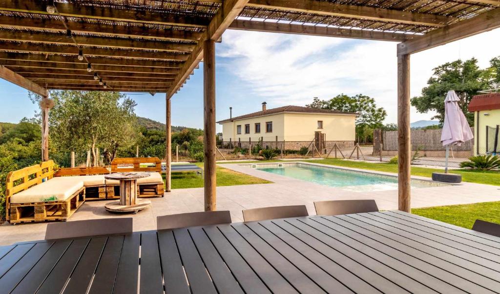 un patio con mesa, sillas y piscina en Can Pons De Dalt Casa rural a la Selva, en Girona