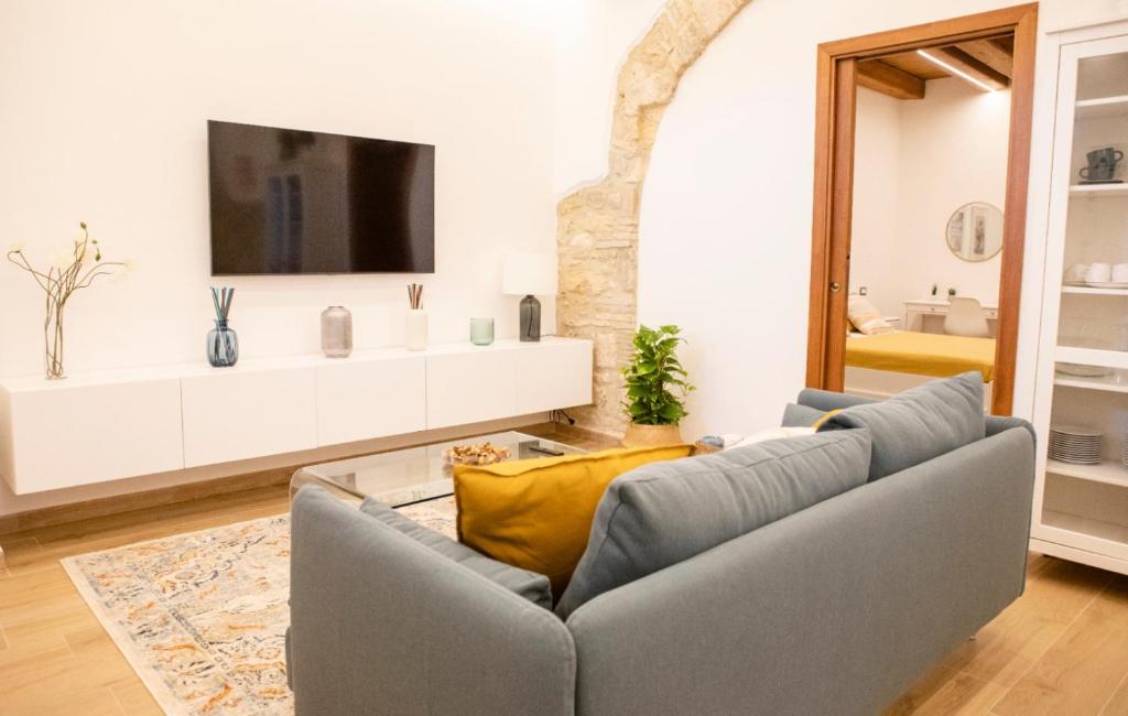 ein Wohnzimmer mit einem Sofa und einem TV in der Unterkunft All’ombra del campanile in Tarquinia