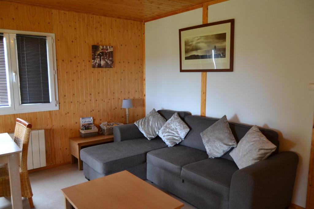 a living room with a couch and a table at Beautiful lake view 3 bedroom chalet. in Saint-Manvieu-Bocage