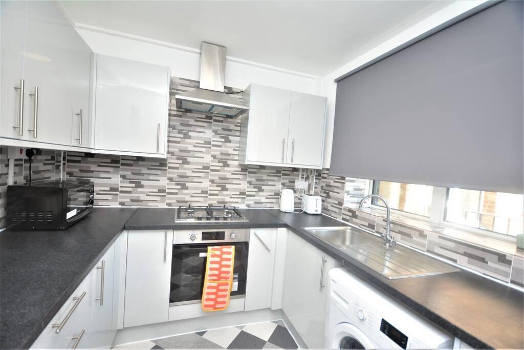 a kitchen with white cabinets and a stove top oven at London Zone 2 Two Bedroom Apartment in London