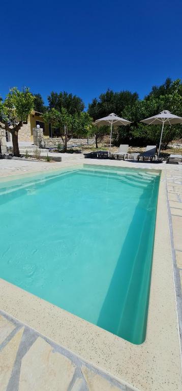 a large blue swimming pool with chairs and umbrellas at Lithines Villa go green in Dhafnés