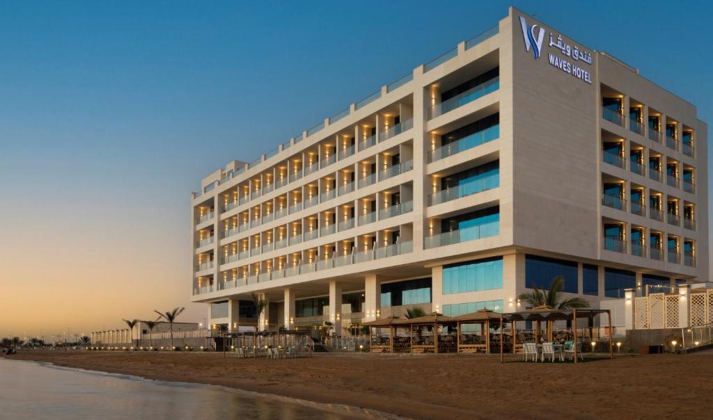 a hotel on the beach next to the ocean at Waves Hotel in Umm Lajj
